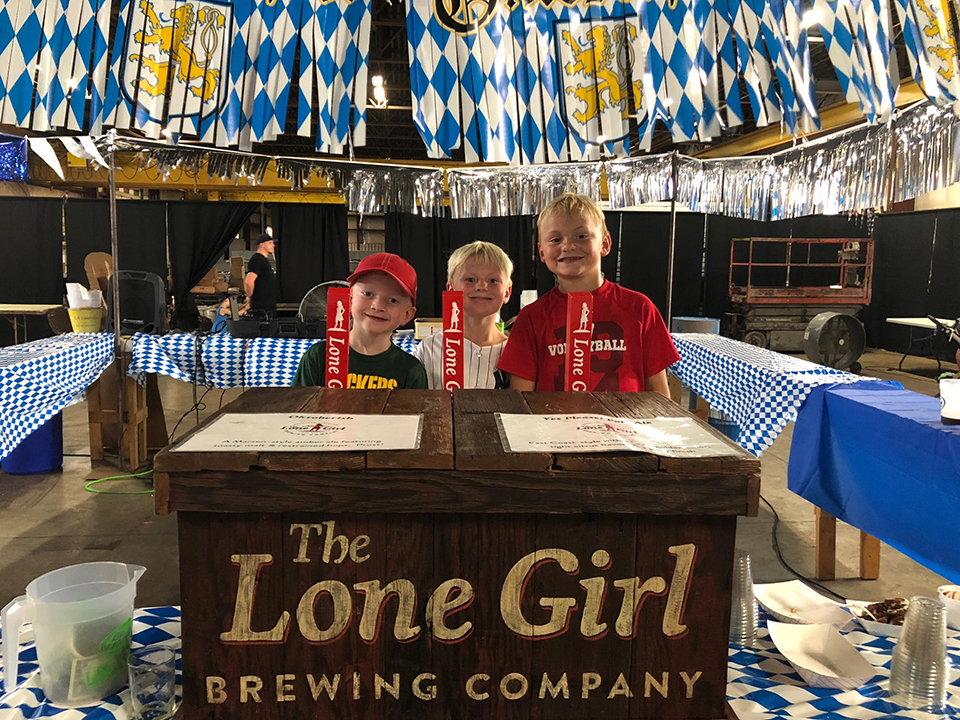 Three kids Home Brew Event in front of Lone Girl Beer Taps